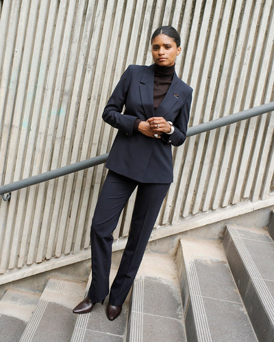 Tenue professionnelle femme avec tailleur bleu marine, veste ceinturée cintrée, gilet sans manches et pantalon droit.