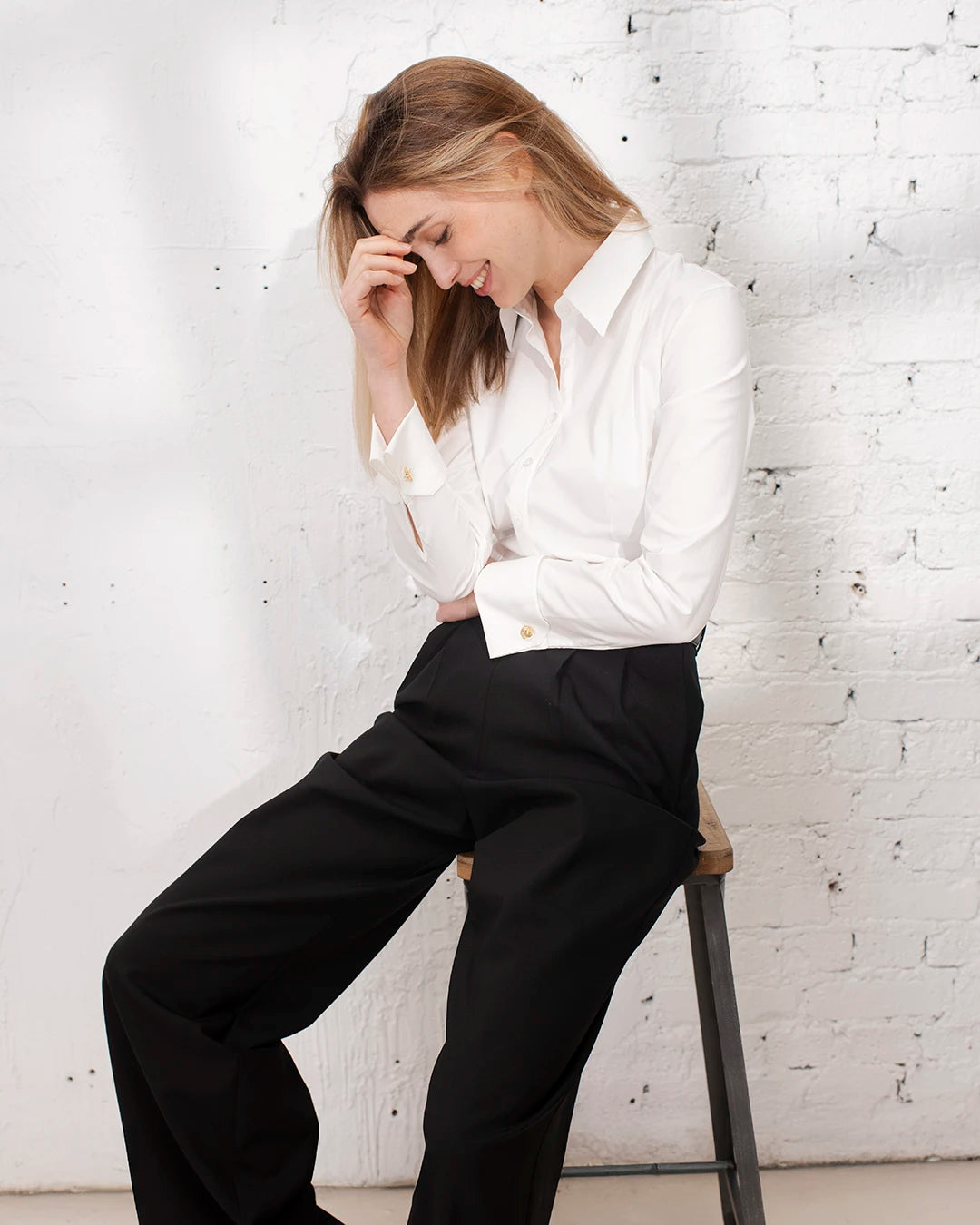 Pantalon tailleur large noir porté avec chemise blanche cintrée pour une tenue de travail élégante.